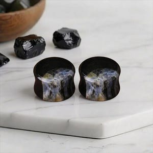 Puede incluir: Un letrero de madera rústica con la palabra "Welcome" en letras blancas. El letrero es rectangular y presenta un acabado envejecido, sugiriendo un estilo vintage o de granja. Para decoración del hogar.