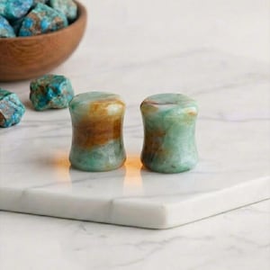 May include: A white ceramic mug with a black handle and the text "But First, Coffee" in a black, handwritten-style font. The mug is on a white surface.