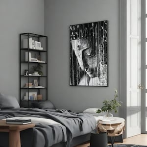 May include: Black and white framed artwork featuring a serene Buddha face with closed eyes. The image has a textured, dripped paint effect, creating a unique artistic style. The artwork is displayed in a modern bedroom setting.