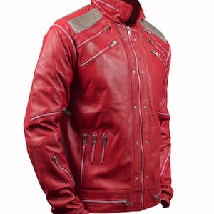Pode incluir: Uma jaqueta de couro vermelho vibrante com v&aacute;rios z&iacute;peres prateados e detalhes de ombro com tachas prateadas. A jaqueta apresenta uma gola alta e uma silhueta ajustada, mostrando um estilo ousado e moderno.