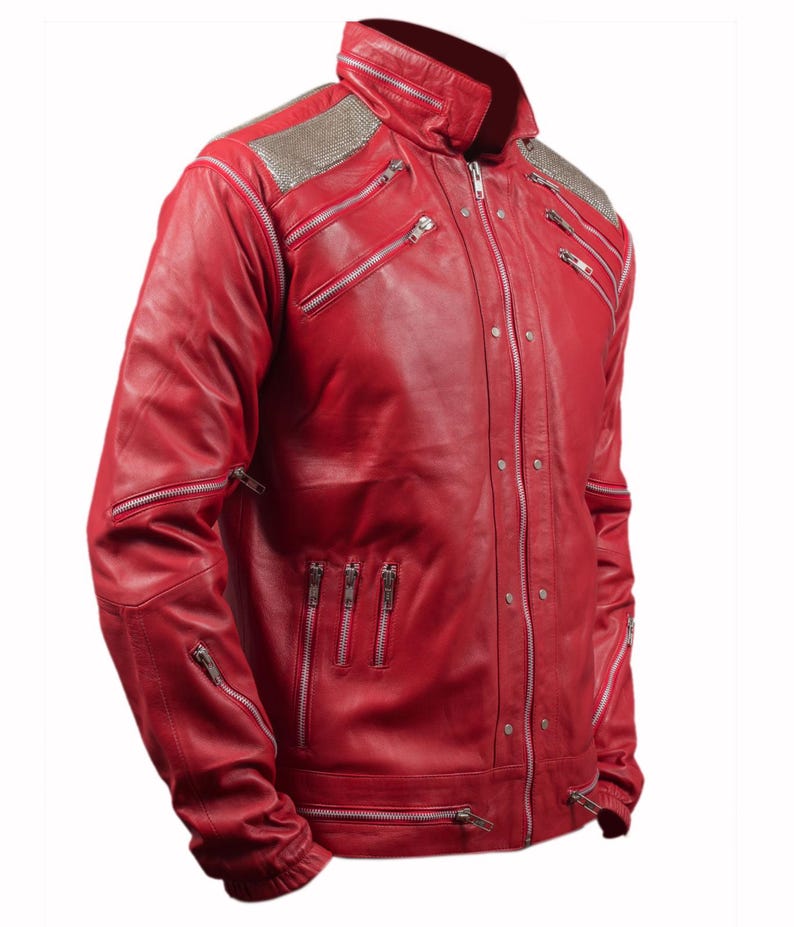 Pode incluir: Uma jaqueta de couro vermelho vibrante com v&aacute;rios z&iacute;peres prateados e detalhes de ombro com tachas prateadas. A jaqueta apresenta uma gola alta e uma silhueta ajustada, mostrando um estilo ousado e moderno.