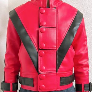 May include: A bright red jacket with black accents. The jacket features a high collar, decorative buttons, and a black stripe design across the shoulders and chest. The jacket has a belt at the waist and cuffs.