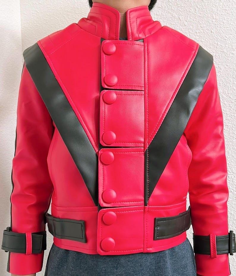 May include: A bright red jacket with black accents. The jacket features a high collar, decorative buttons, and a black stripe design across the shoulders and chest. The jacket has a belt at the waist and cuffs.