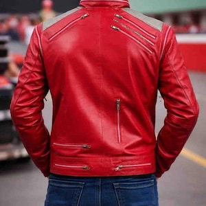 Pode incluir: Casaco de couro vermelho com v&aacute;rios z&iacute;peres prateados e um detalhe cinza no ombro. O casaco &eacute; combinado com jeans azuis. A vista traseira mostra o design e os detalhes do casaco.