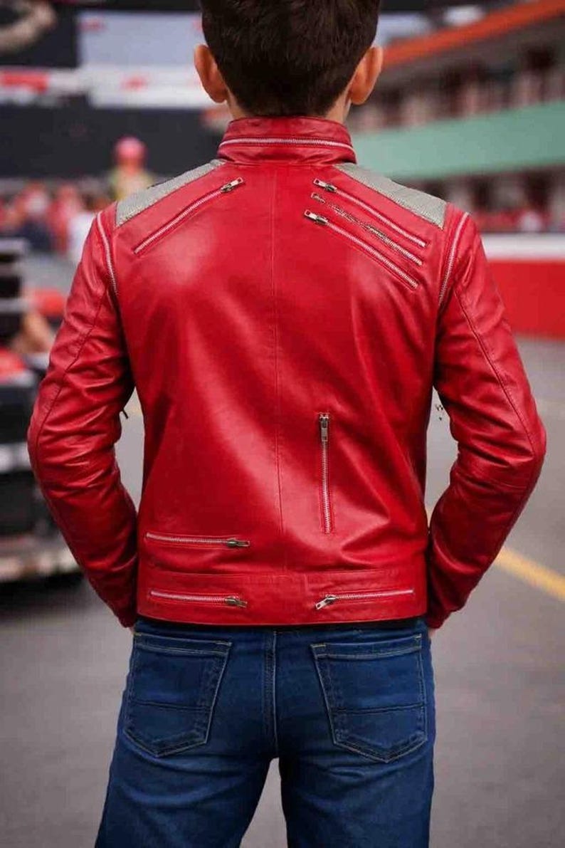 Pode incluir: Casaco de couro vermelho com v&aacute;rios z&iacute;peres prateados e um detalhe cinza no ombro. O casaco &eacute; combinado com jeans azuis. A vista traseira mostra o design e os detalhes do casaco.