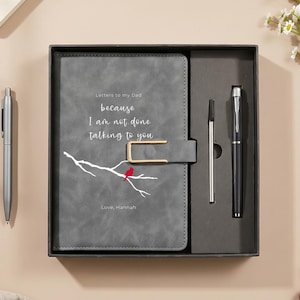 May include: A grey journal with a gold-toned metal clasp, featuring a white branch illustration, a red cardinal, and the text "Letters to my Dad because I am not done talking to you" and "Love, Hannah." The set includes a black pen and a refill.