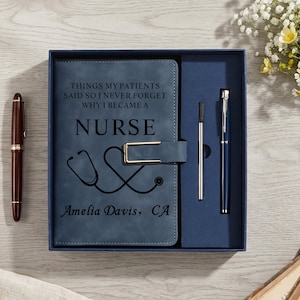 May include: A blue notebook set in a box featuring a gold-tone clasp, a stethoscope graphic, and the text: Things my patients said so I never forget why I became a nurse, Amelia Davis, CA. Includes a blue pen and a silver metal refill.