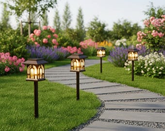 May include: A garden pathway lined with four solar-powered pathway lights. The lights have a dark brown finish and a lantern-style design with a warm, inviting glow. The pathway is made of gray stone, and the background features lush greenery and colorful flowers.