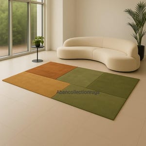 以下が含まれることがあります： オレンジ、黄色、緑の色合いの幾何学模様の長方形ラグ。ラグはいくつかの長方形のパネルで構成されています。「Abancollectionrugs」という文字がラグに表示されています。