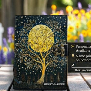 K&ouml;nnte beinhalten: Ein dunkelblaues Notizbuch mit einem Baum- und Monddesign. Das Cover zeigt einen gro&szlig;en gelben Mond und einen Baum mit komplizierten &Auml;sten. Das Notizbuch hat einen Metallverschluss und der Text "SHERRY GARDNER" steht unten. Ein Schild sagt "Personalisierter Name verf&uuml;gbar".
