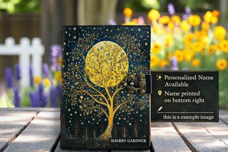 K&ouml;nnte beinhalten: Ein dunkelblaues Notizbuch mit einem Baum- und Monddesign. Das Cover zeigt einen gro&szlig;en gelben Mond und einen Baum mit komplizierten &Auml;sten. Das Notizbuch hat einen Metallverschluss und der Text "SHERRY GARDNER" steht unten. Ein Schild sagt "Personalisierter Name verf&uuml;gbar".
