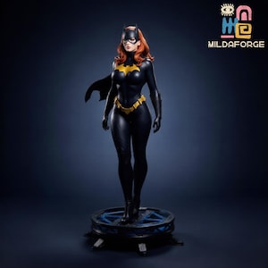 May include: A detailed statue of a female superhero in a black and yellow costume, cape, and mask. The figure has red hair and is standing on a circular platform with blue accents. The logo "MILDAFORGE" is visible in the upper right corner.