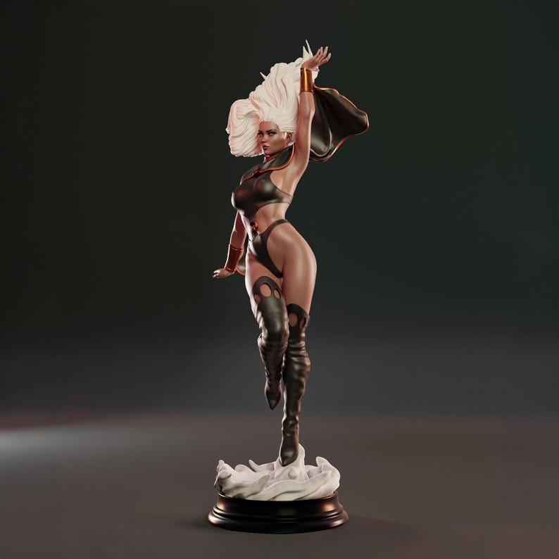 May include: A detailed figurine of a female superhero in a dynamic pose. She wears a black bodysuit, knee-high boots, and a flowing cape. Her white hair is styled upwards, and she stands on a cloud-like base atop a black circular stand.
