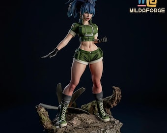 May include: A detailed figurine of a female character in a dynamic pose, wearing a green military-style outfit with shorts and boots. The figure has blue hair and is standing on a textured base. The logo "MILDAFORGE" is visible in the upper right corner.