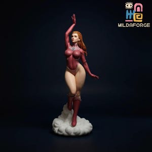 Puede incluir: Una figura roja y rosa de una mujer con un atuendo de superhéroe, posando sobre una base en forma de nube. La figura tiene el pelo largo y rojo y está en una pose dinámica con un brazo levantado. El logo "MILDAFORGE" está en la esquina superior derecha.