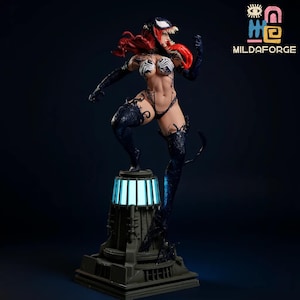 May include: A detailed statue of a female character with red hair and a Venom-inspired design. The figure is posed dynamically atop a pedestal with a glowing blue light. The statue is dark with black and white accents.