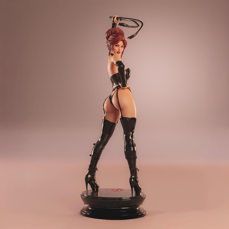 May include: A figurine of a woman in a black outfit, holding a whip. The figure has red hair and is wearing thigh-high boots. The figurine is standing on a black base.