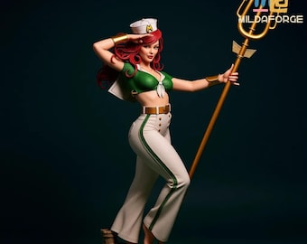 May include: A detailed figurine of a woman in a sailor-inspired outfit, saluting. She wears a green top, white pants with green trim, and a white hat. She holds a gold trident and stands on a small base. The figurine has red hair and is set against a dark teal background.