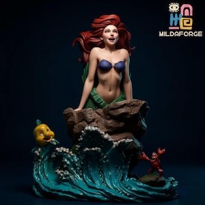 May include: A statue of a mermaid with red hair, wearing a blue seashell bra and a green tail, atop a rock formation. A yellow fish and a red crab are also featured, with a blue wave in the foreground. The statue is from Mildaforge.