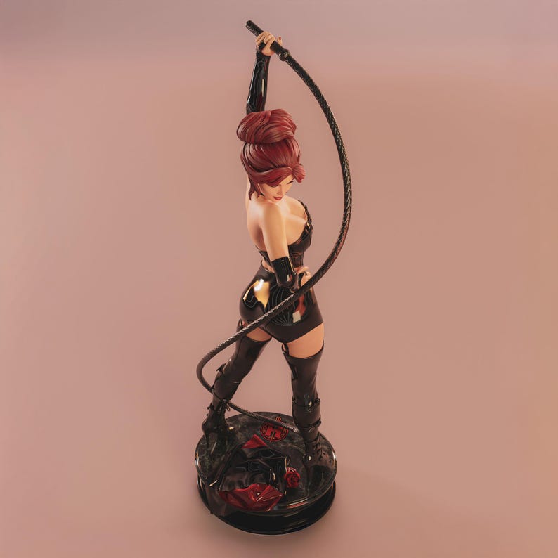 May include: A figurine of a woman with red hair, dressed in a black outfit, holding a whip. The figure stands on a round, black base with red accents. The background is a gradient of pink and peach.