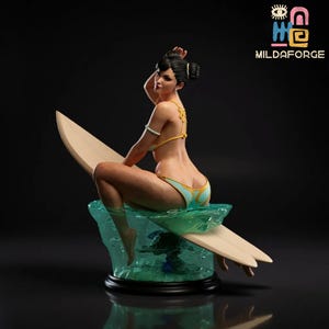 Könnte beinhalten: Detaillierte Figur einer Frau in einem gelb-blauen Bikini, die auf einem Surfbrett sitzt. Die Figur steht auf einem durchscheinenden blauen Sockel, mit dem Logo "MILDAFORGE" oben rechts. Die Frau hat ihr Haar hochgesteckt und schaut über ihre Schulter.