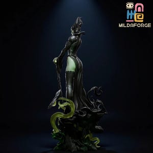 May include: A black figurine of a character with a horned headdress and long, flowing gown. The figure is posed with a staff and stands on a dark base with green accents. The figure is a stylized representation of a fantasy character.