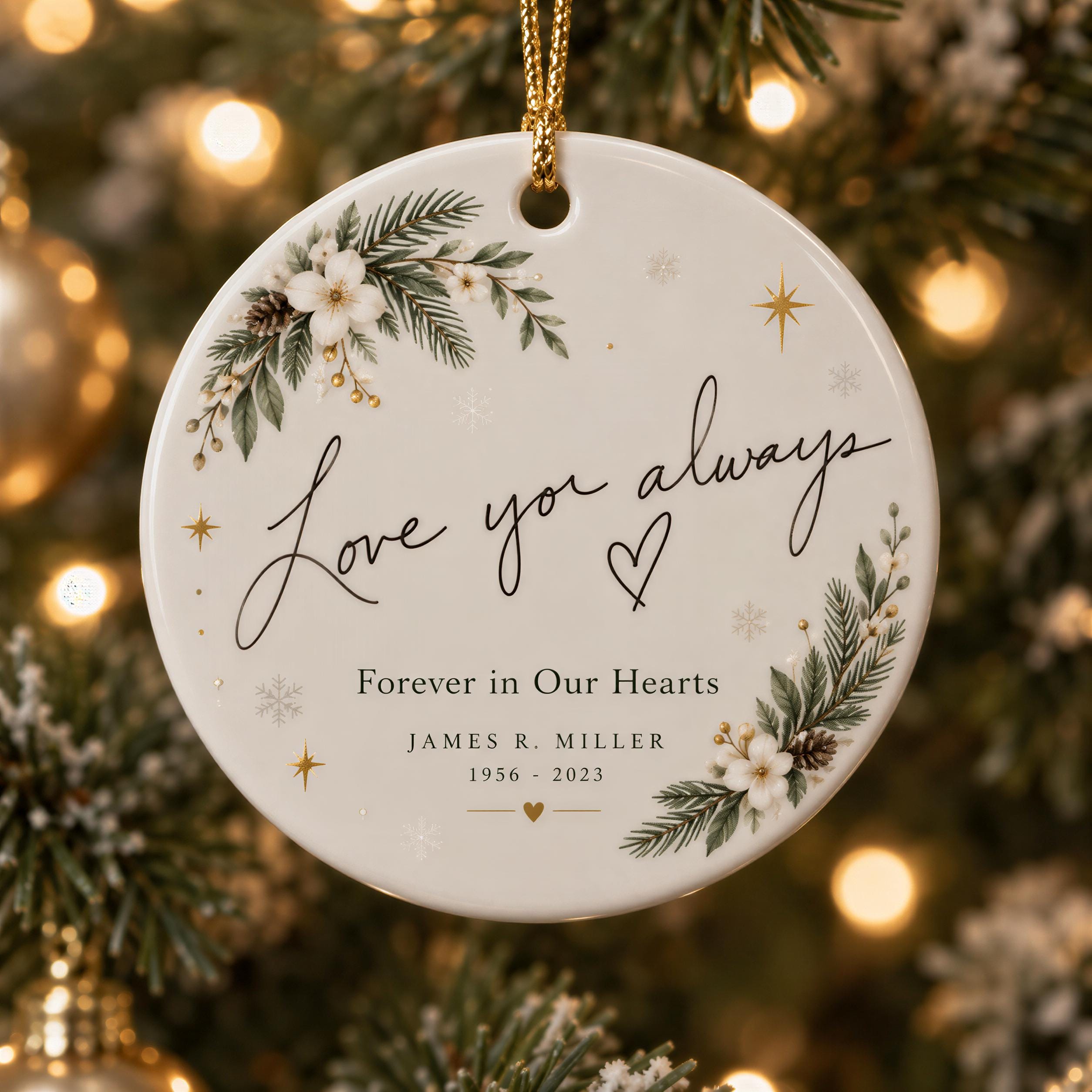 A white ornament with a floral design and the text "Love you always Forever in Our Hearts" hanging on a Christmas tree.