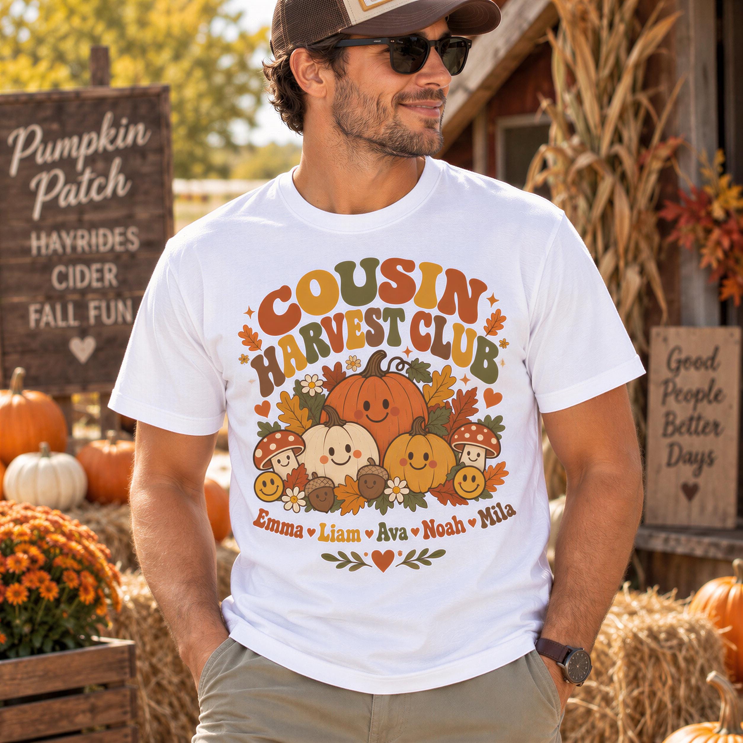 A man wearing a white t-shirt with a graphic design of pumpkins and fall decorations, standing in front of a pumpkin patch.