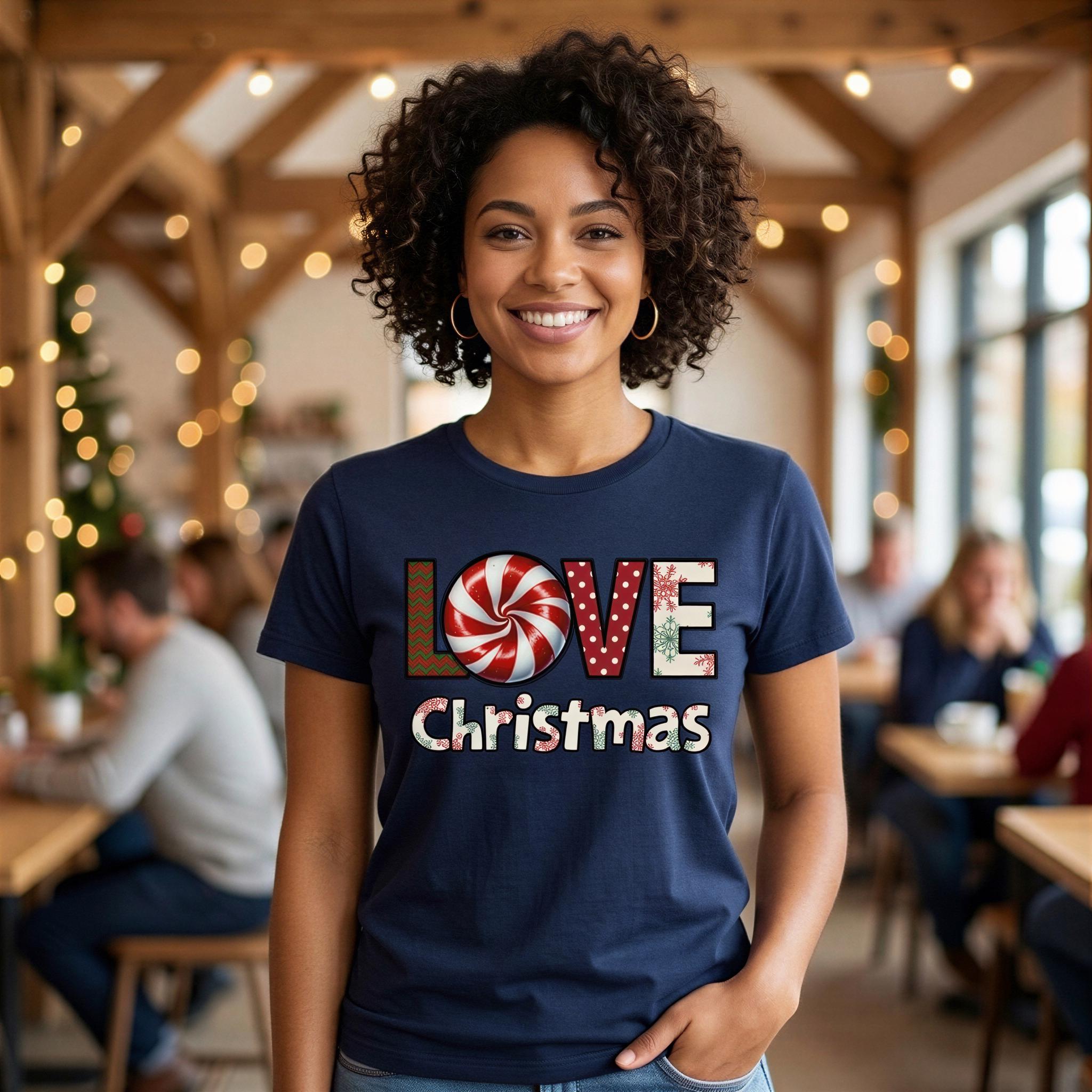 A smiling woman wearing a blue t-shirt with the text "LOVE Christmas" stands in a room with Christmas lights and other people in the background.