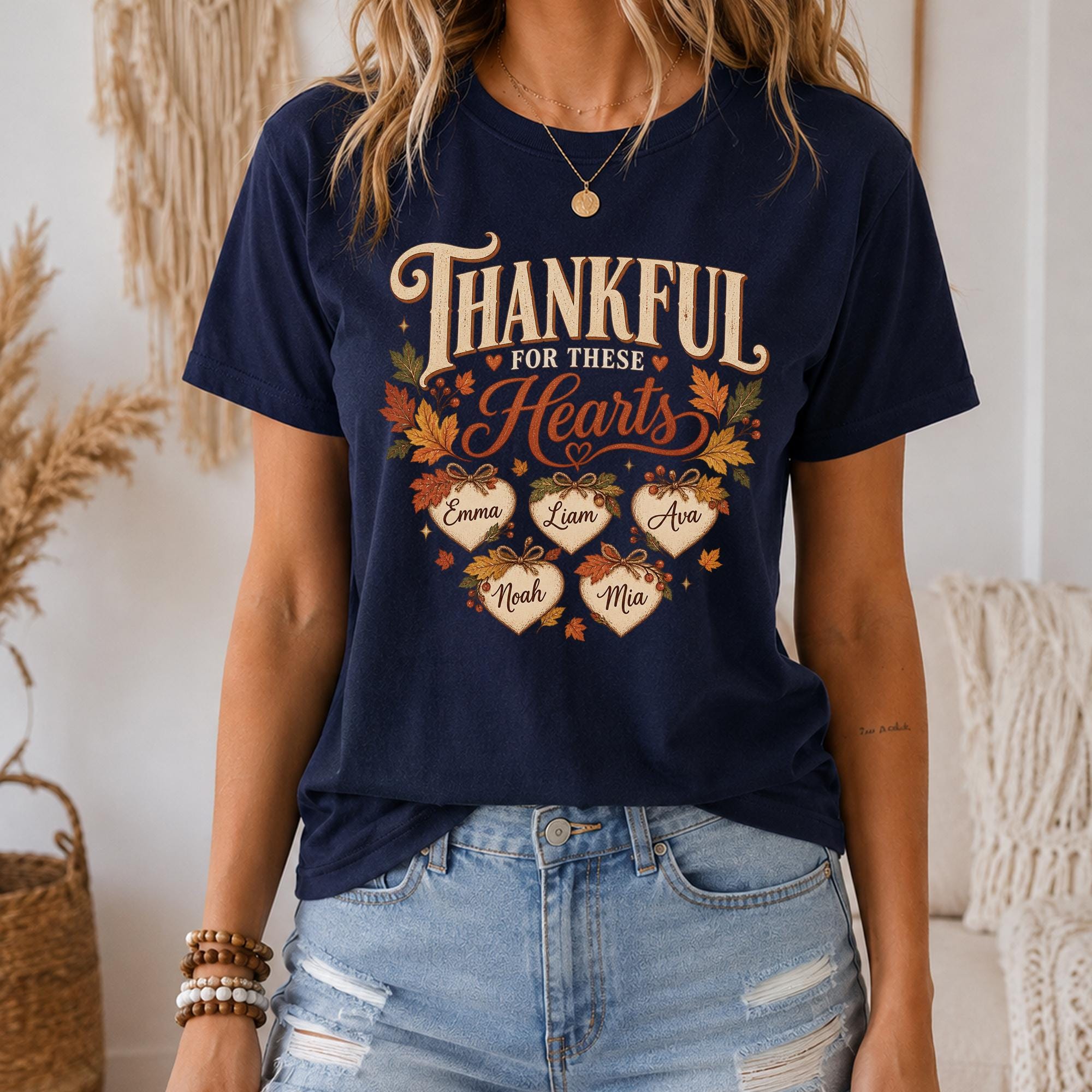 A woman wearing a navy blue t-shirt with a graphic design that says "Thankful for these hearts" and includes the names of five individuals.
