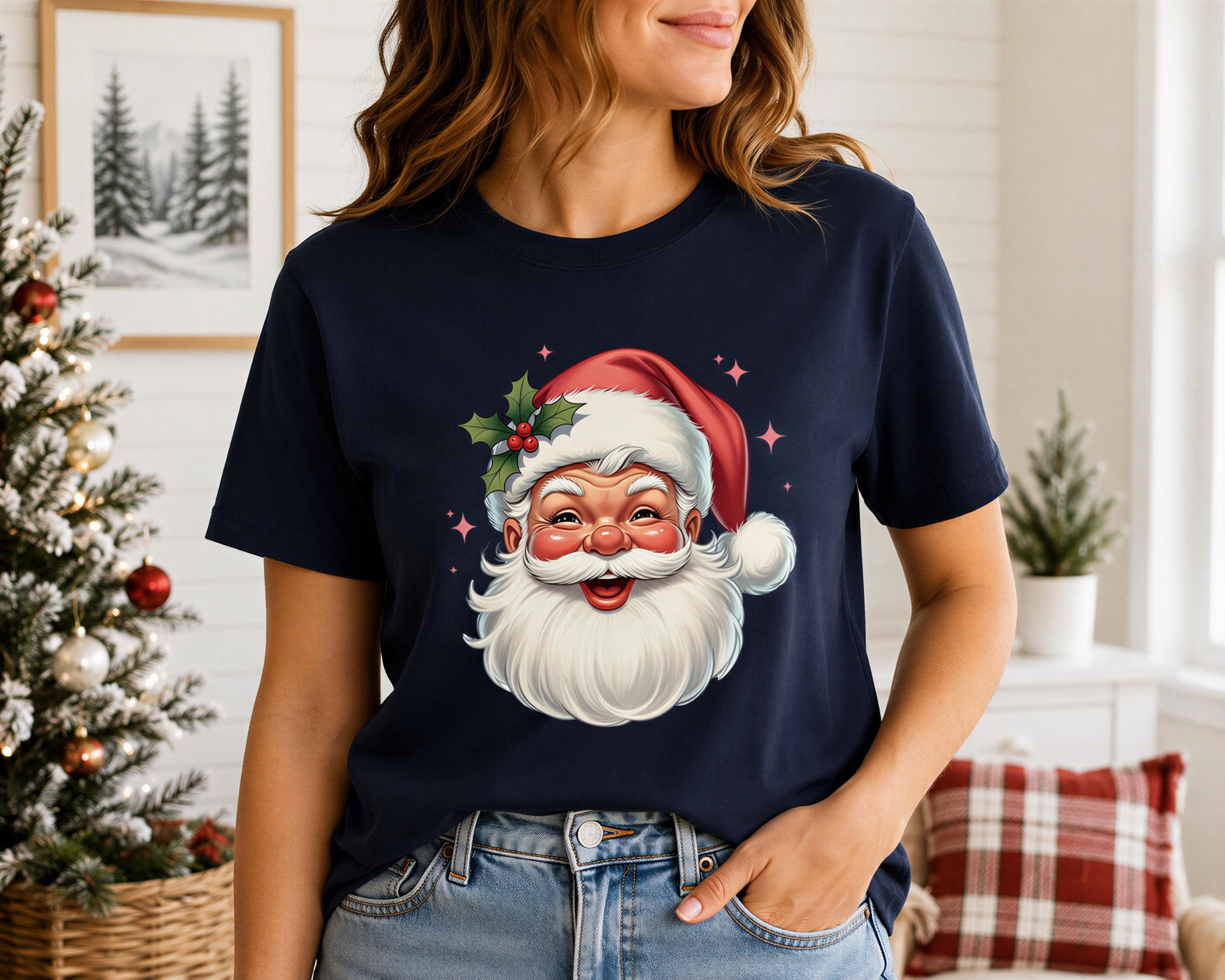 A woman wearing a navy blue t-shirt with a Santa Claus graphic is standing in front of a Christmas tree.