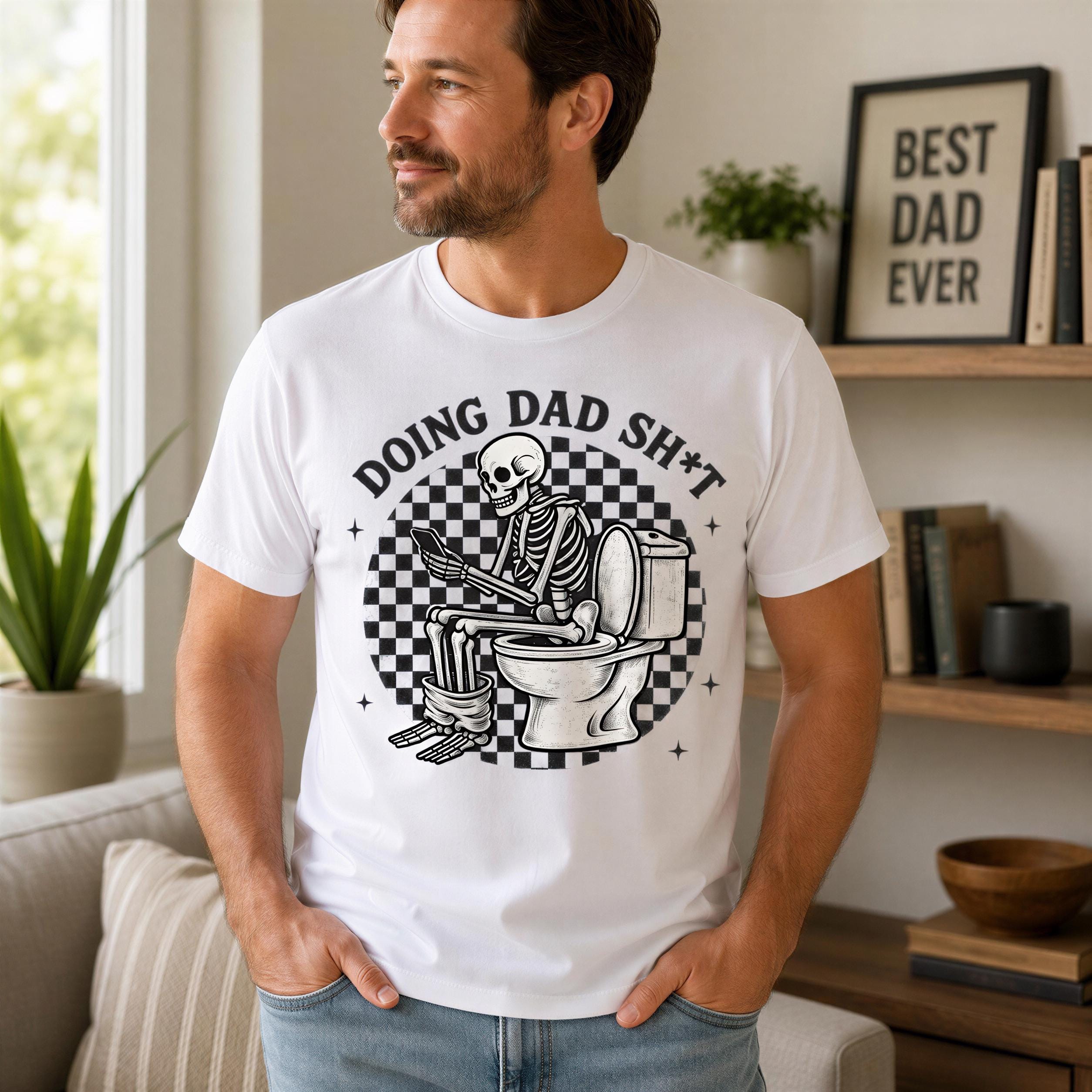 A man wearing a white t-shirt with a graphic design of a skeleton sitting on a toilet and holding a book, with the text "DOING DAD SHIT" printed on it.