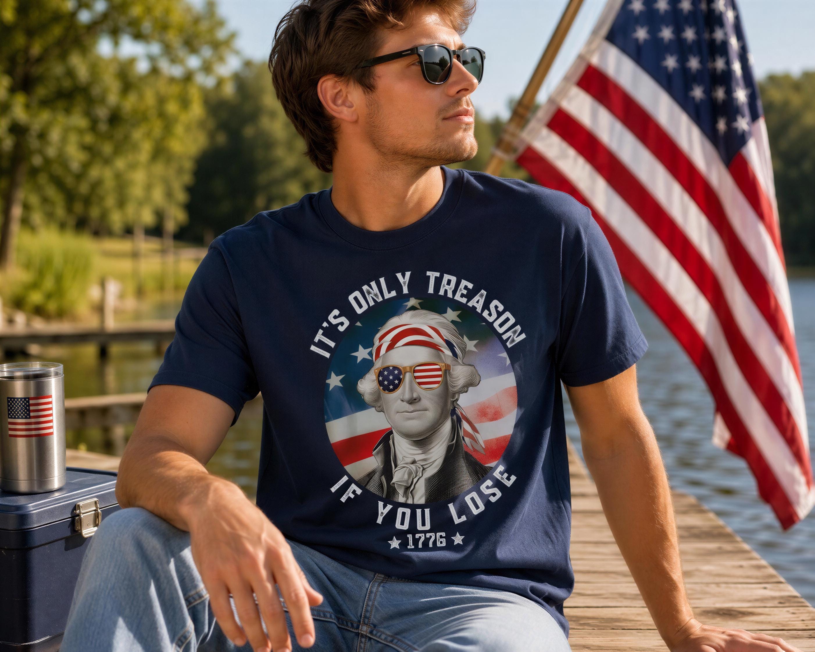A man wearing a navy blue t-shirt with a graphic of a man wearing sunglasses and a bandana, sitting on a dock with an American flag in the background.