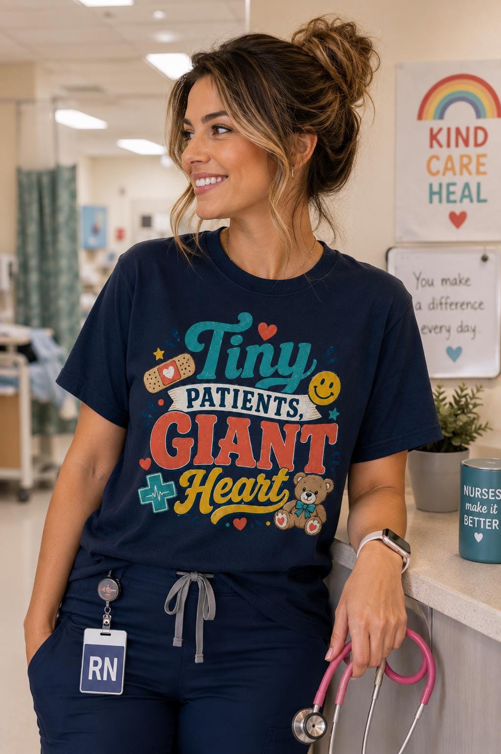 A smiling woman wearing a blue t-shirt with a colorful graphic design and text, standing in a hospital setting.