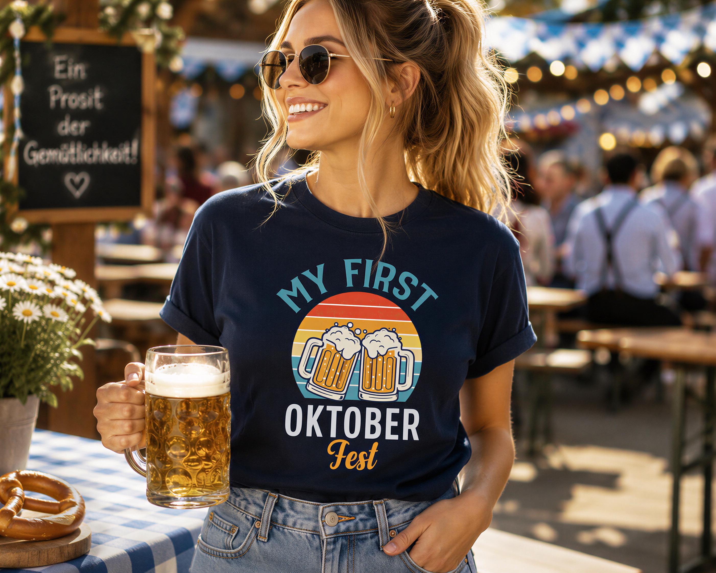 A woman wearing sunglasses and a blue t-shirt with a graphic of beer mugs is holding a glass of beer and smiling at the camera.