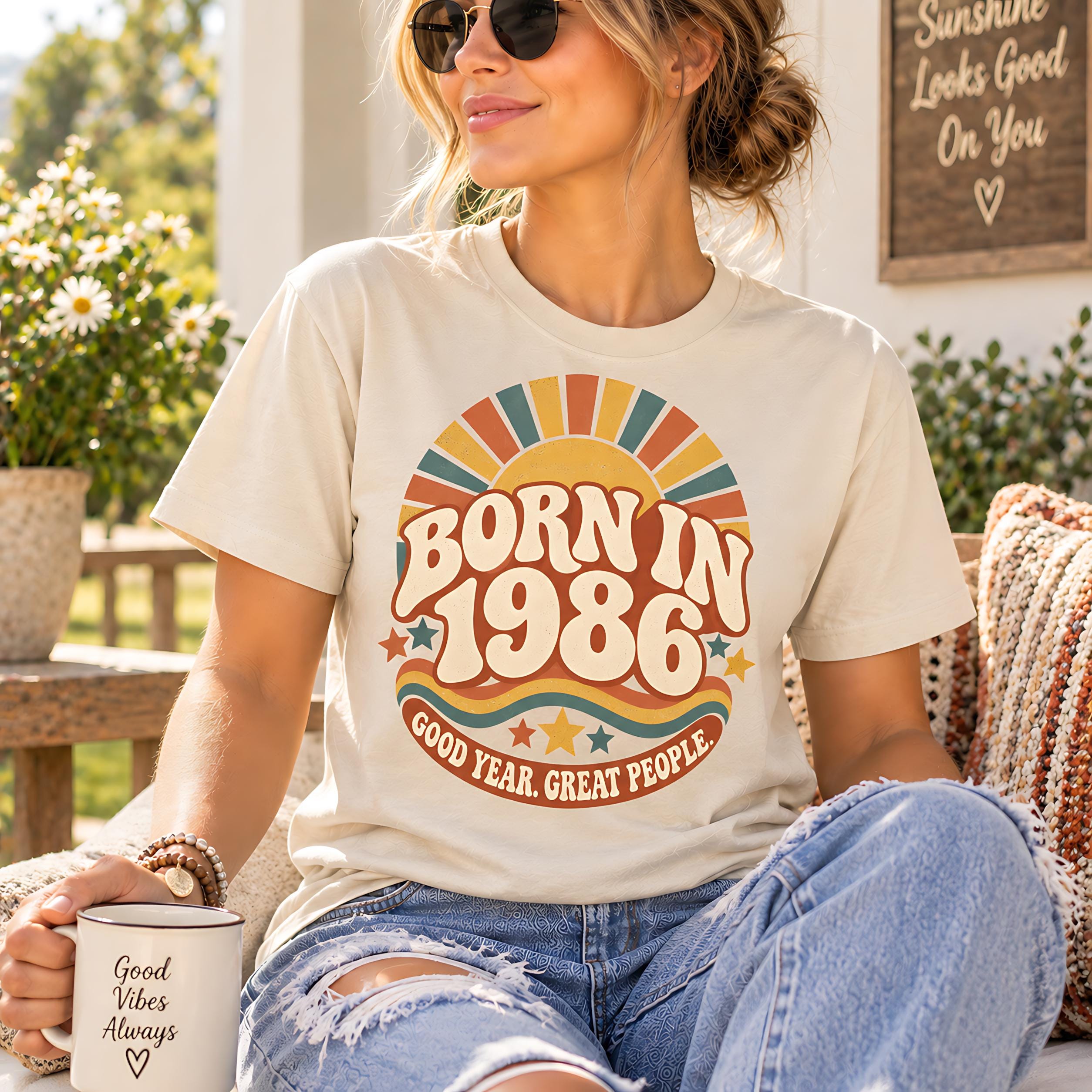 A woman wearing a t-shirt with a retro-style design and sunglasses is sitting on a bench, holding a coffee mug.