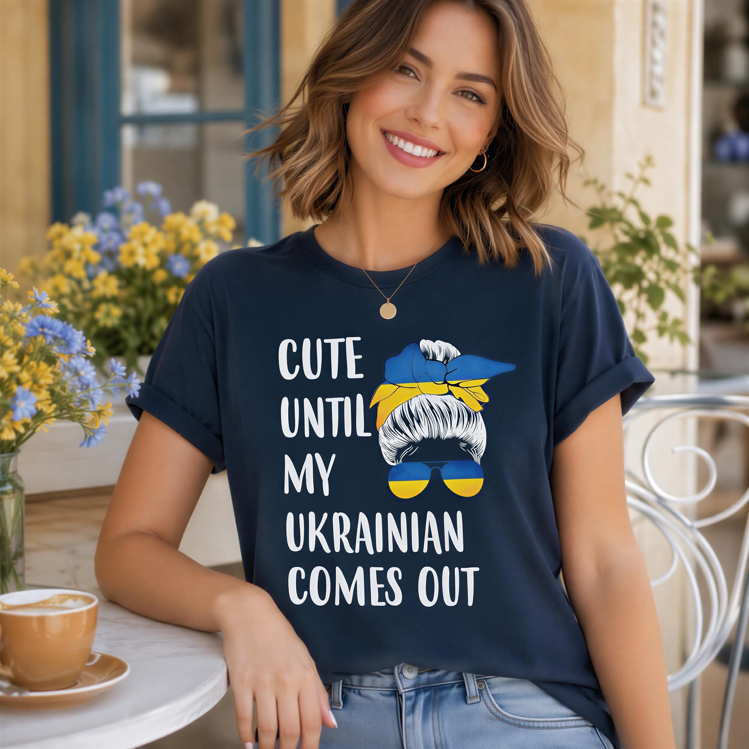 A woman wearing a blue t-shirt with text and a graphic of a woman's face smiling at the camera.