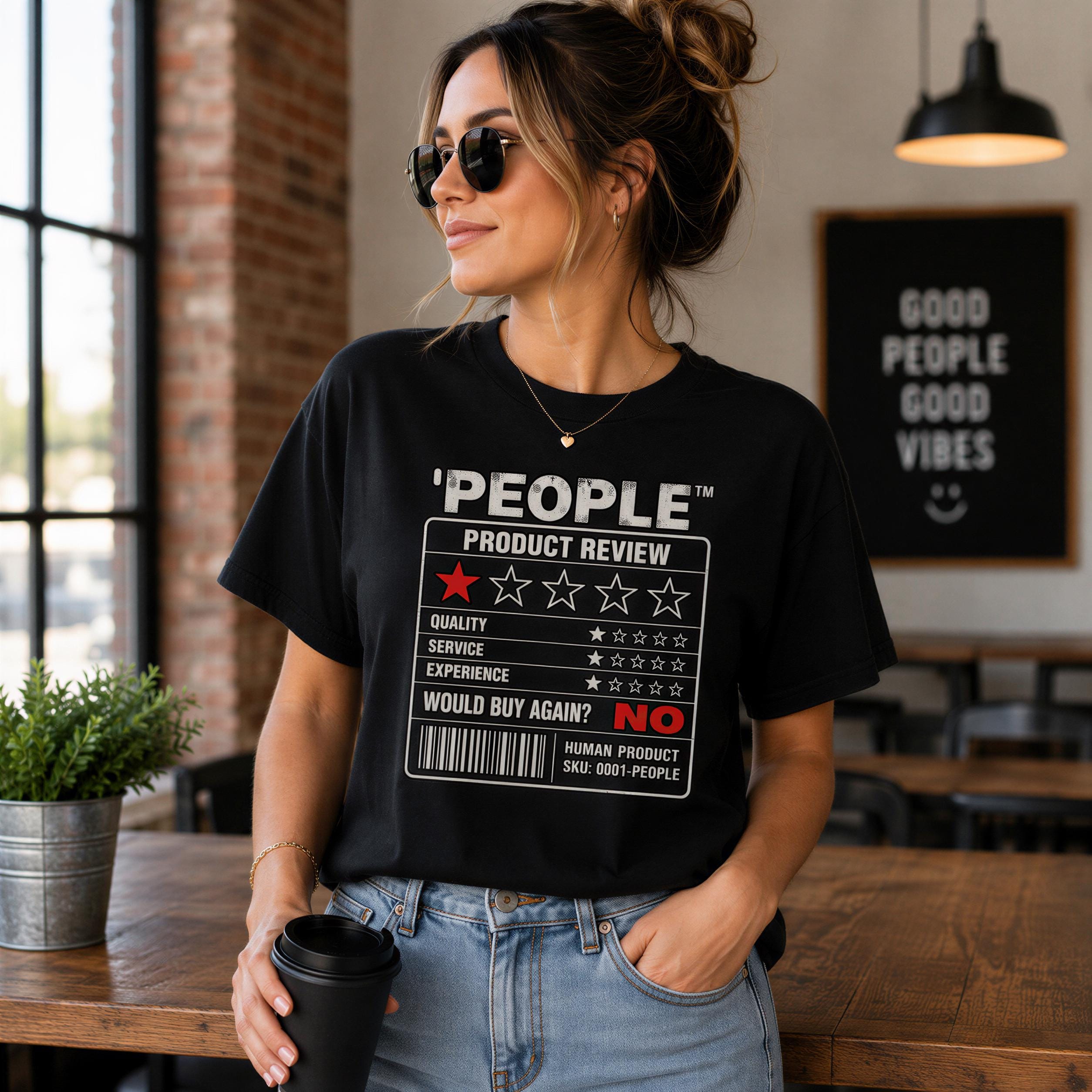 A woman wearing a black t-shirt with a graphic design and holding a black coffee cup, standing in a room with a brick wall and a window.
