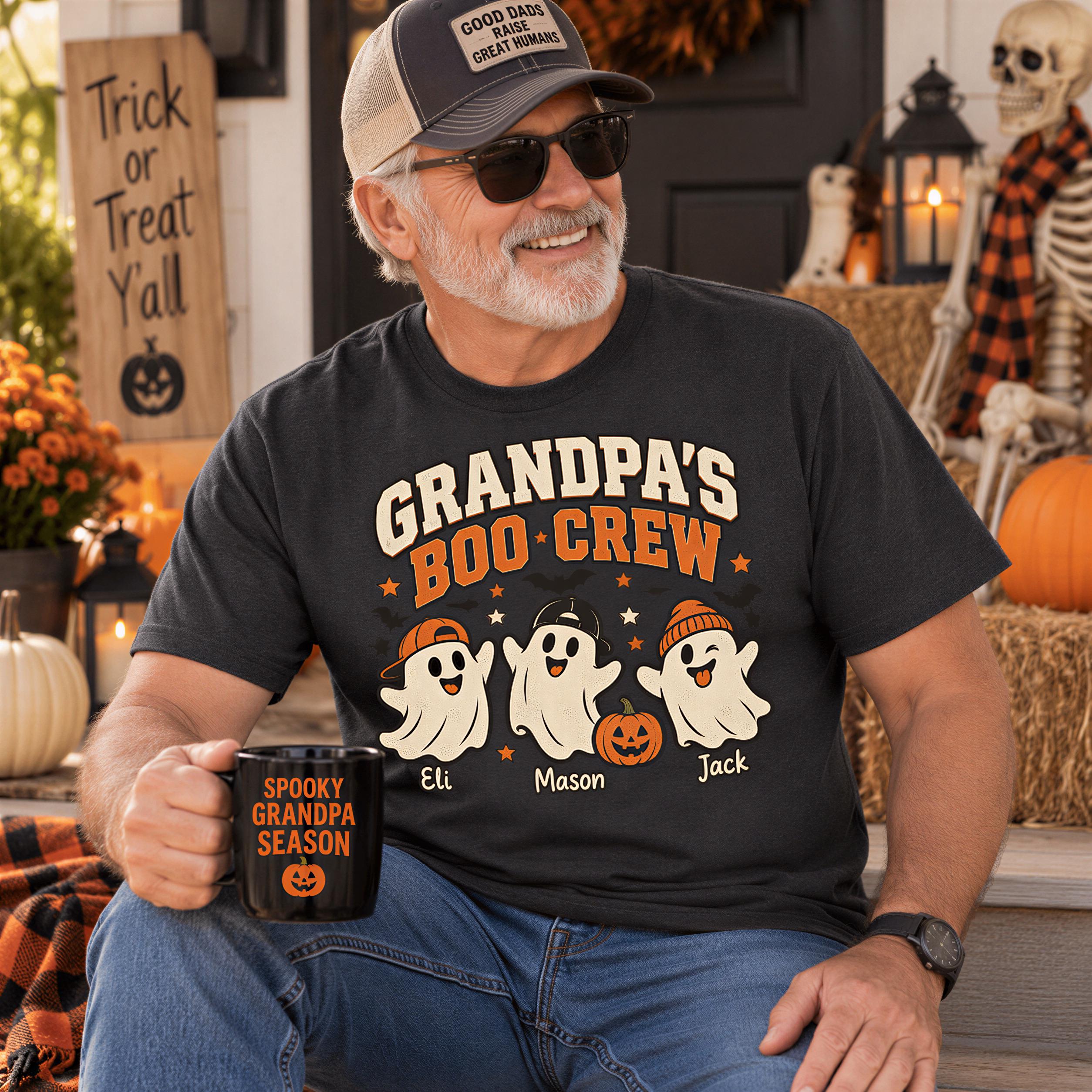 A man wearing a black t-shirt with a graphic of three ghost characters and holding a mug labeled "Spooky Grandpa Season" is sitting on a porch surrounded by Halloween decorations.