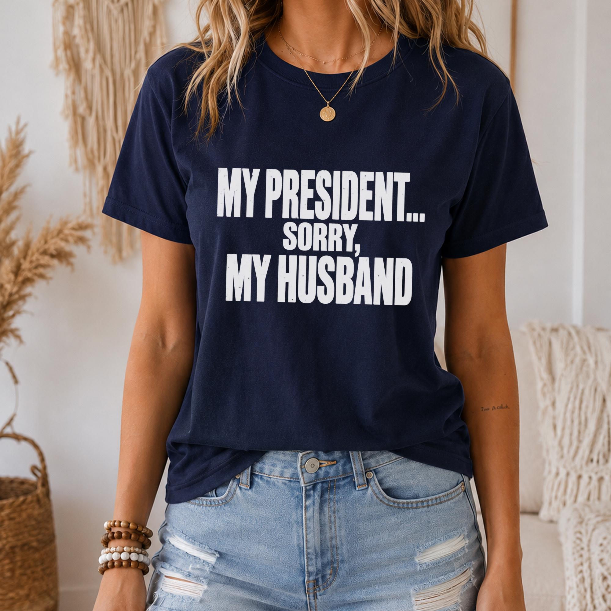 A woman wearing a navy blue t-shirt with the text "MY PRESIDENT... SORRY, MY HUSBAND" printed on it.
