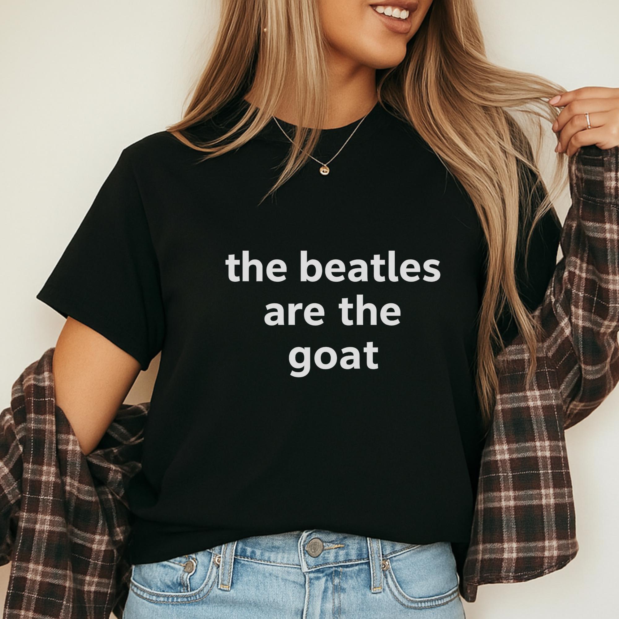 A woman wearing a black t-shirt with the text "the Beatles are the goat" printed on it.