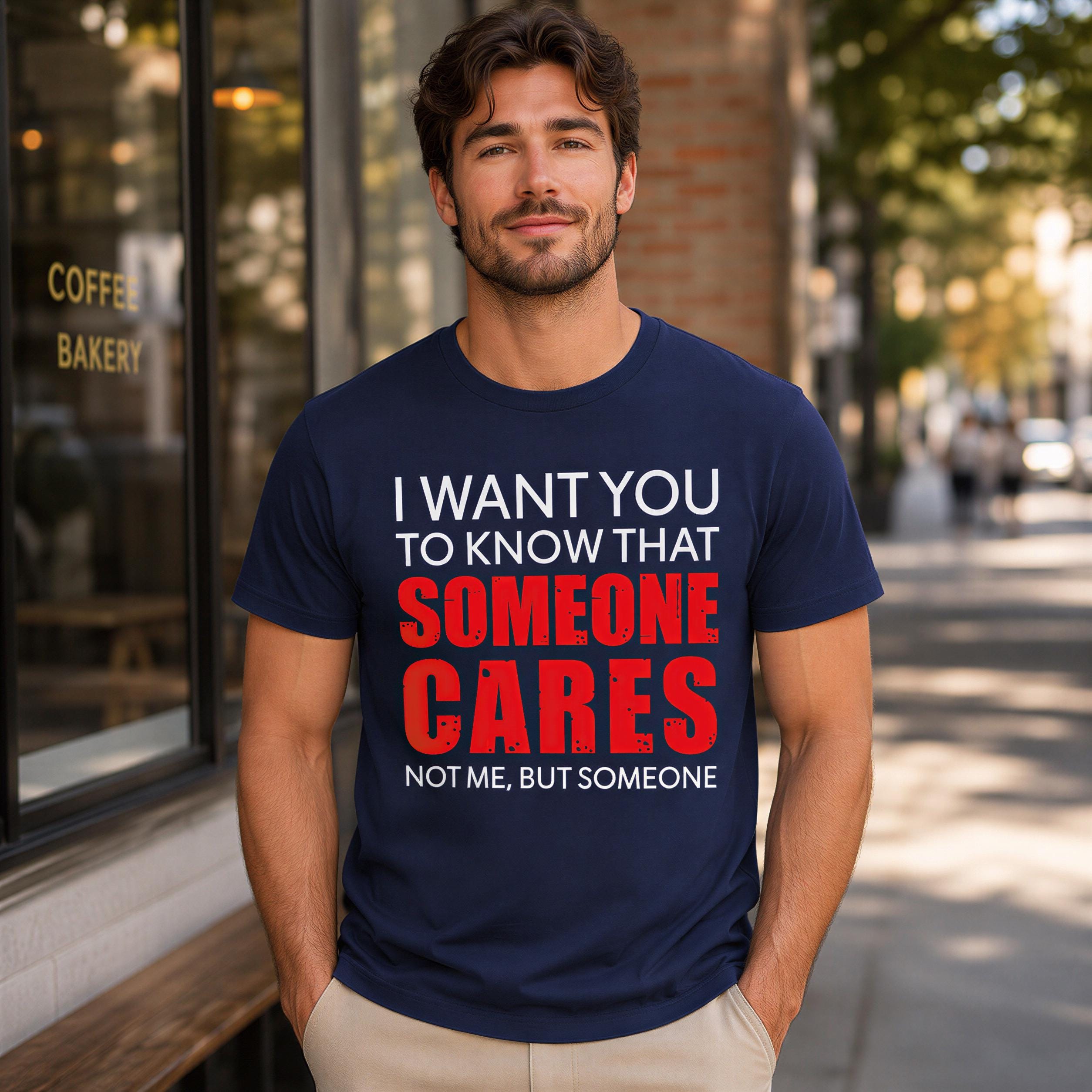 A man wearing a navy blue t-shirt with text on it stands in front of a building.