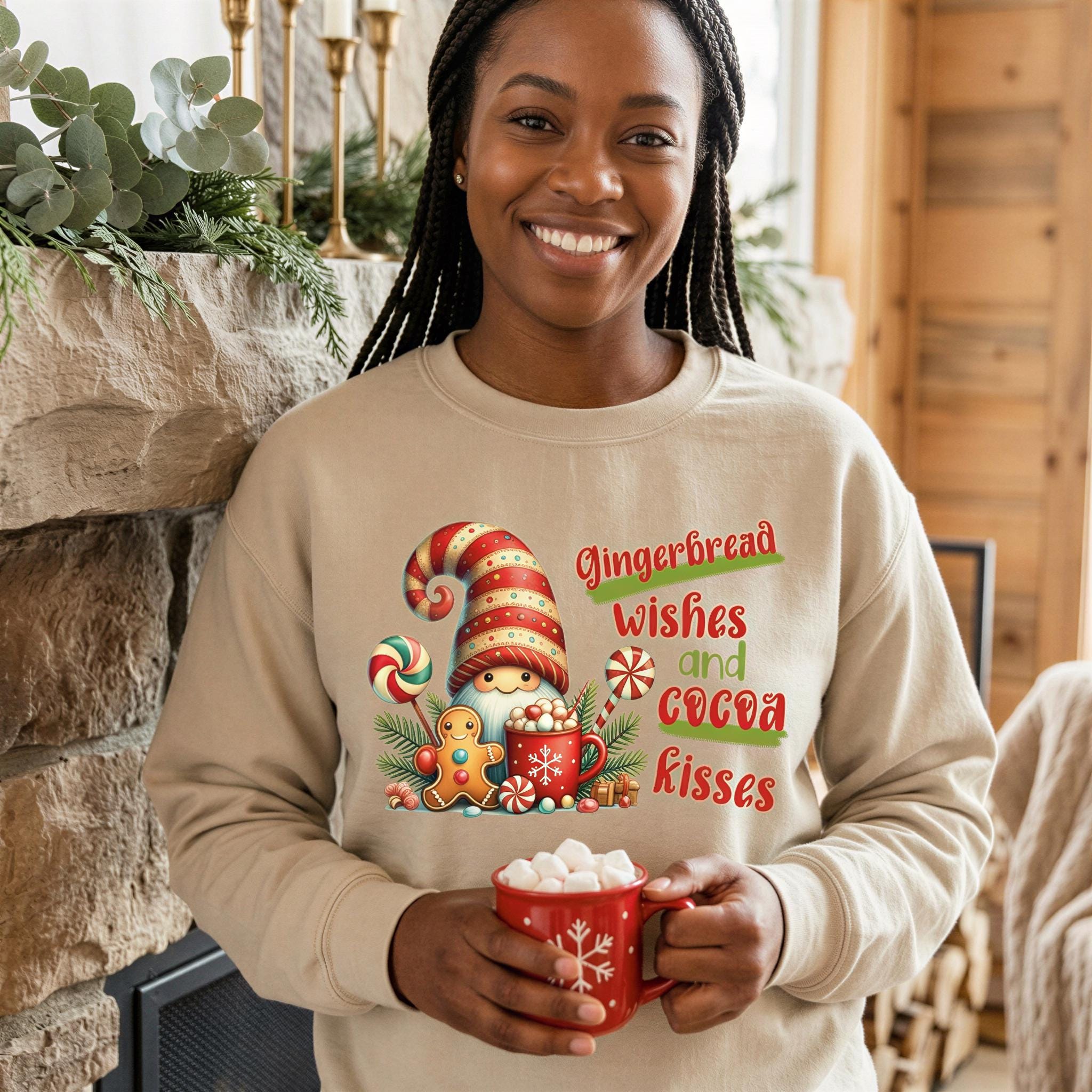A smiling woman wearing a beige sweater with a graphic of a gingerbread man and text that says "Gingerbread wishes and cocoa kisses". She is holding a mug of hot chocolate and is standing in front of a fireplace.