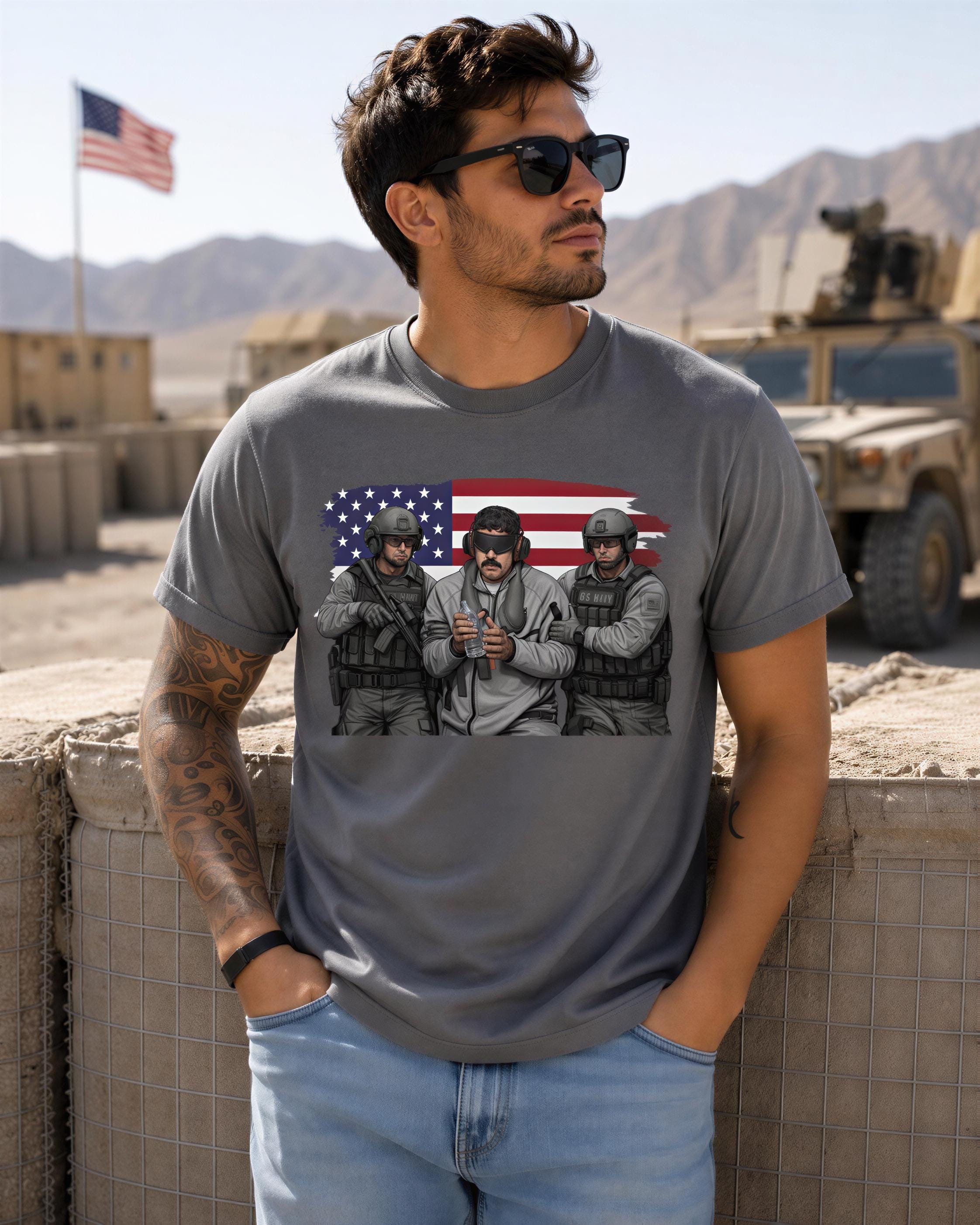 A man wearing a gray t-shirt with an American flag design and three soldiers posing in front of a military vehicle.