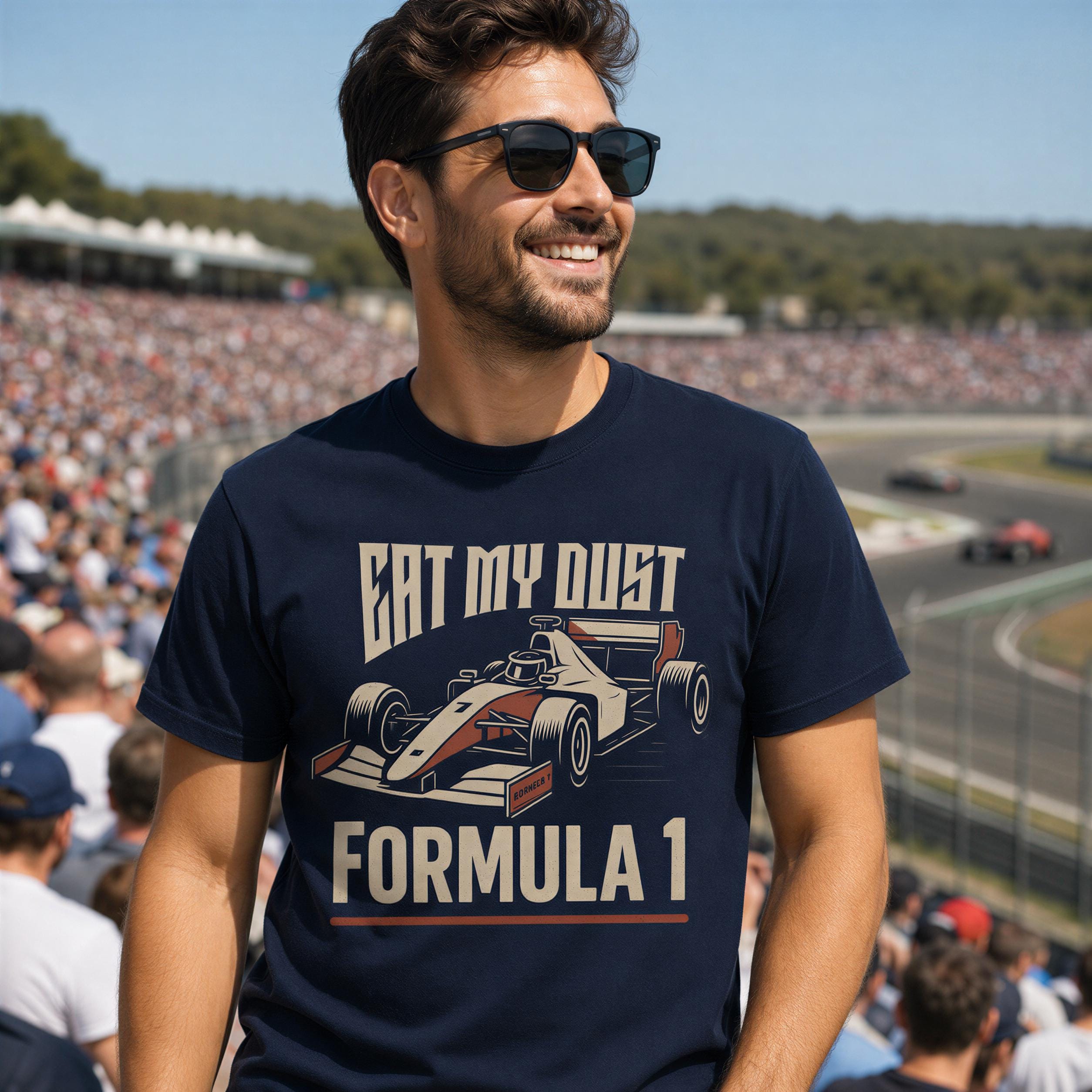 A man wearing a navy blue t-shirt with a graphic of a Formula 1 race car and the text "Eat my dust Formula 1" is standing in a crowded stadium.