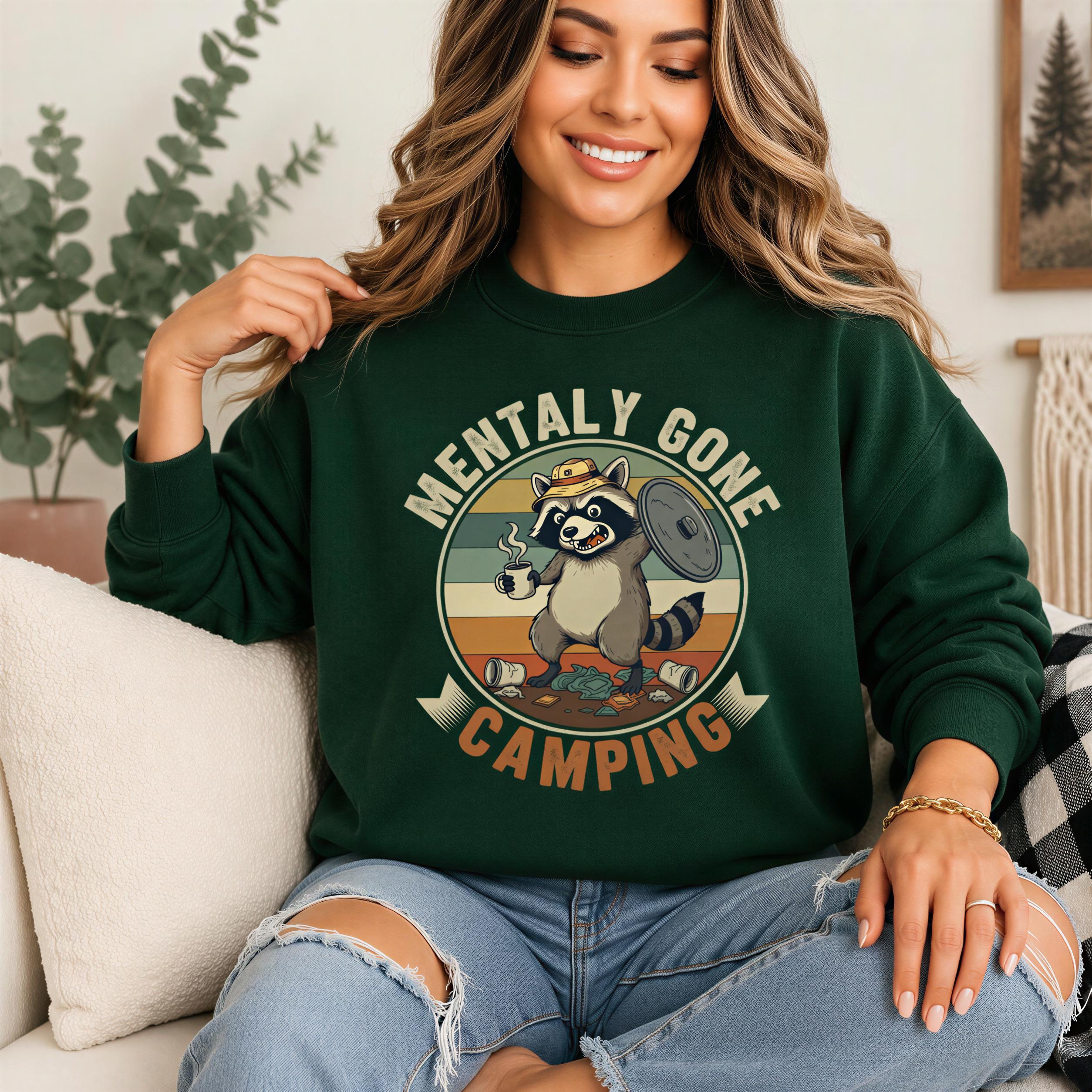 A woman wearing a green sweatshirt with a graphic of a raccoon and the text "Mentally Gone Camping" is sitting on a couch.