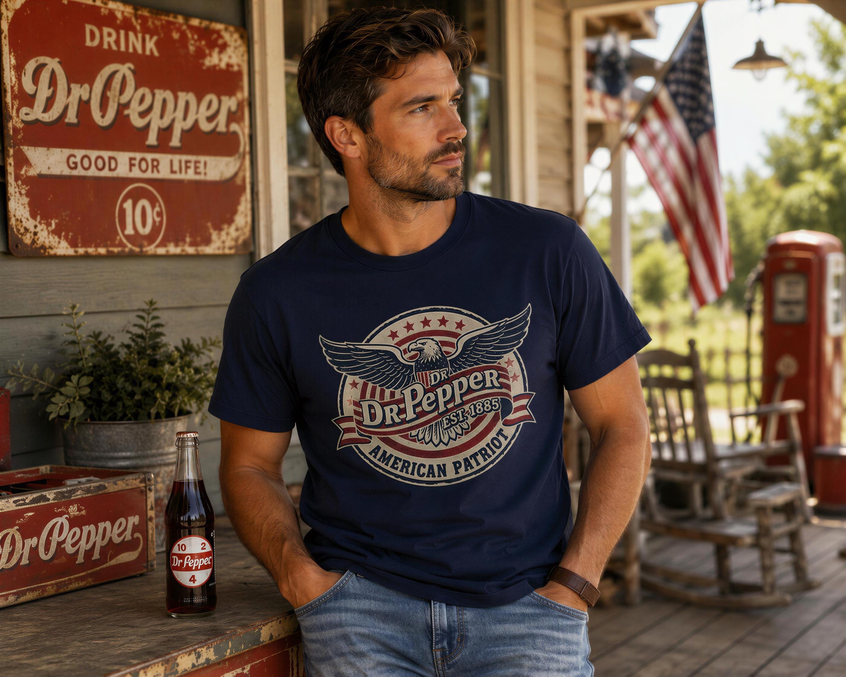 A man wearing a blue t-shirt with a graphic of Dr Pepper and an American flag stands on a porch, with a vintage Dr Pepper sign and a red and white striped flag visible in the background.