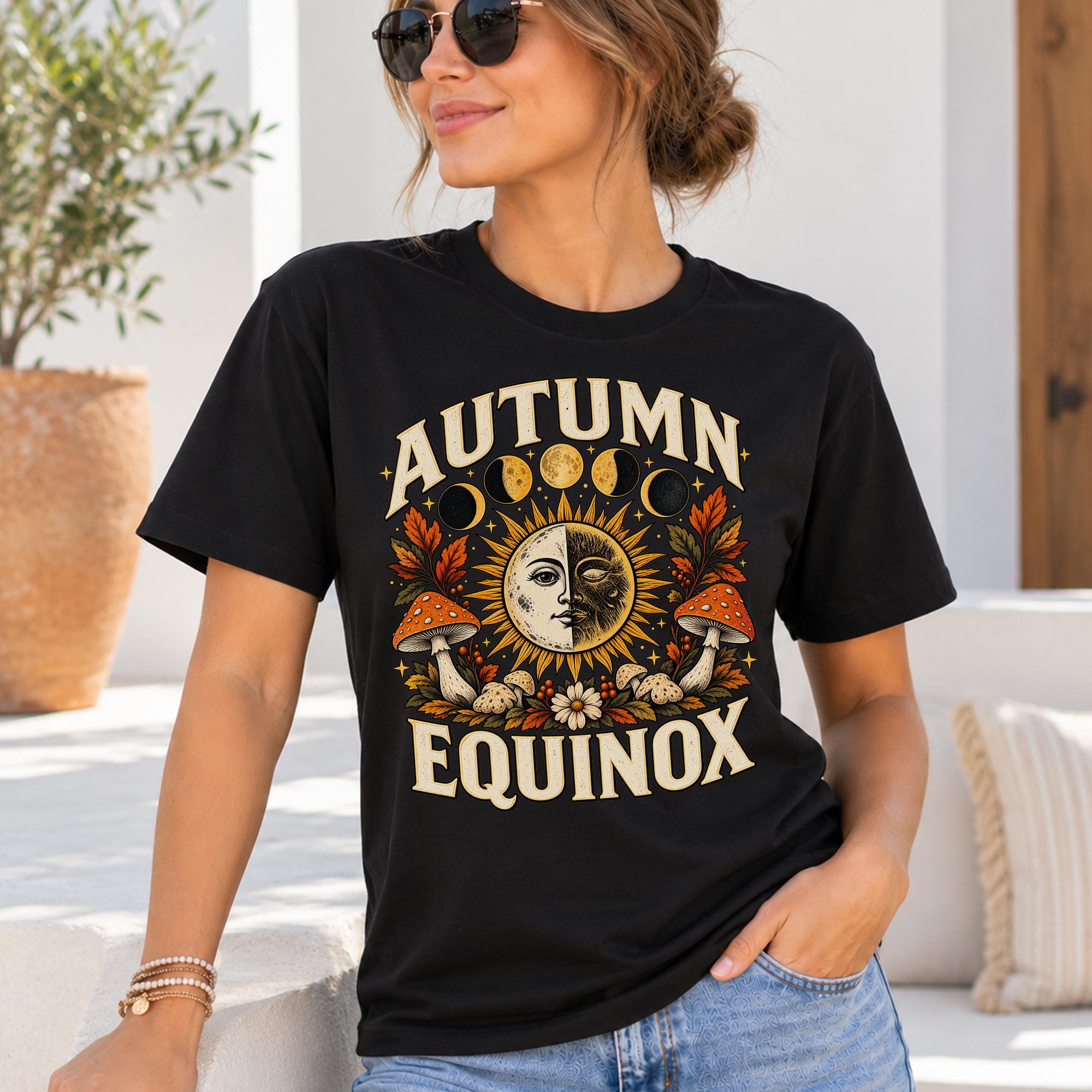 A woman wearing a black t-shirt with a graphic design that says "Autumn Equinox" and features a sun, moon, and mushrooms.