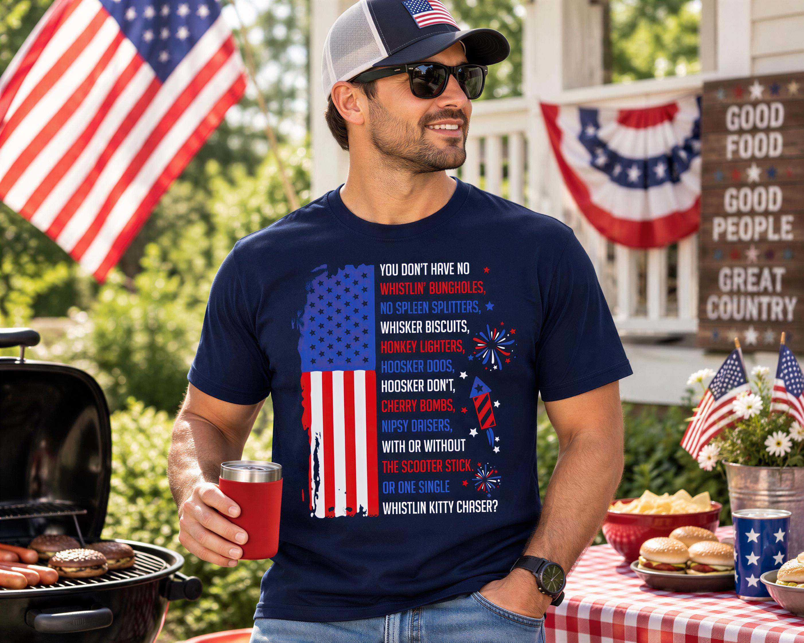 A man wearing a patriotic t-shirt and sunglasses stands in front of a table with American flags and food, holding a red cup.