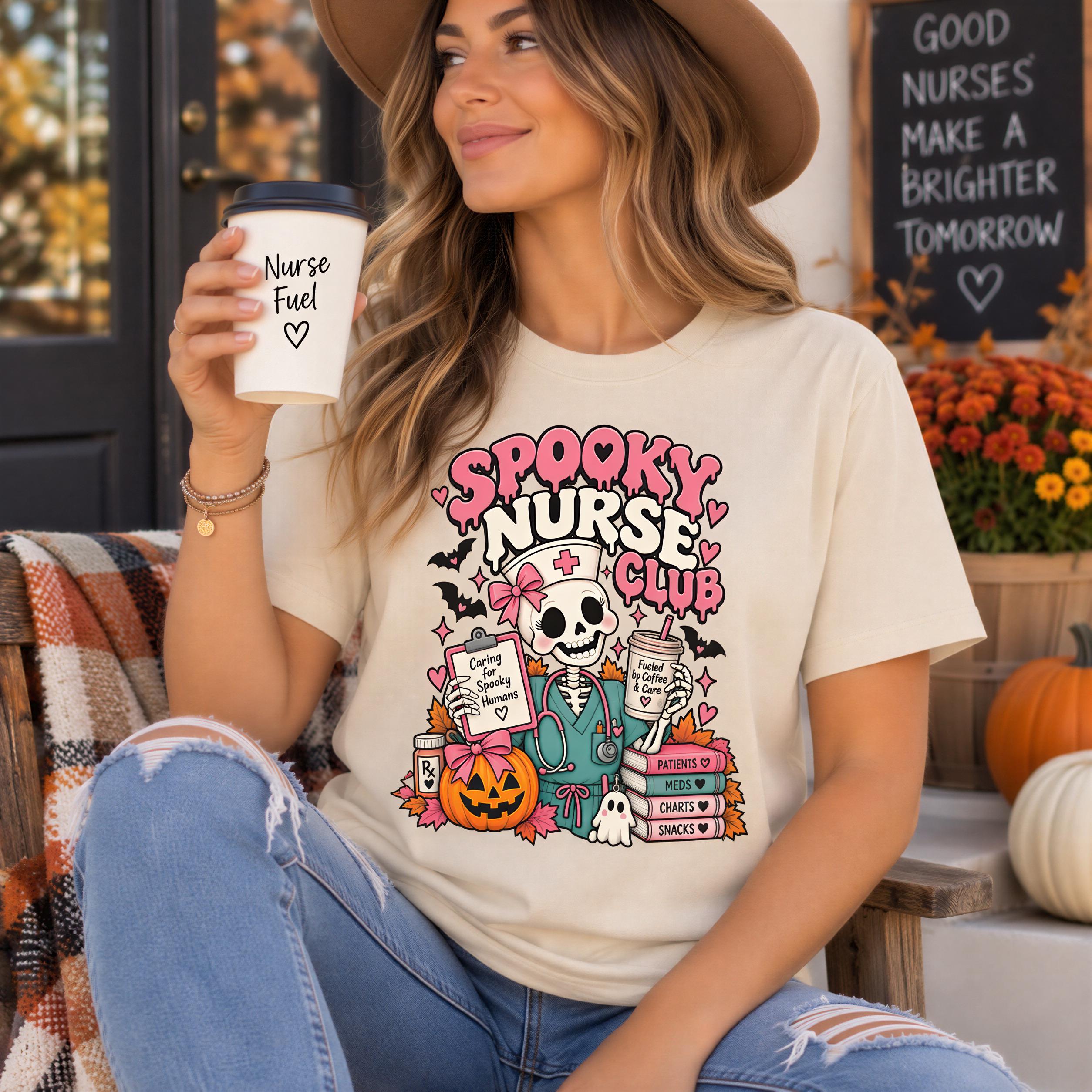 A woman wearing a white t-shirt with a cartoon character and text, holding a coffee cup, and sitting on a bench with a pumpkin decoration in the background.